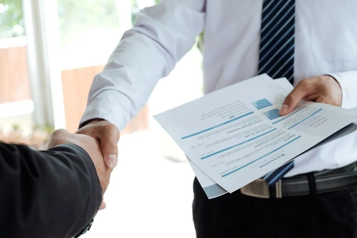 Two people shaking hands over a sheet of paper.