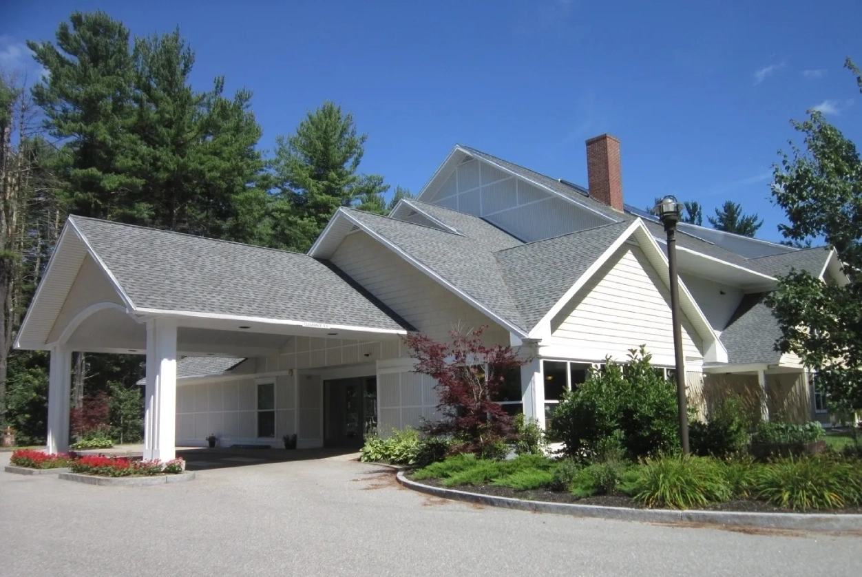 A large white house with a driveway and trees.